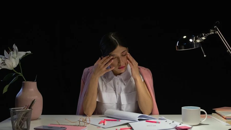 늦은 밤 사무실 책상에서 지친 표정으로 앉아 있는 사람
