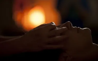 어두운 조명 아래 얼굴과 목을 감싼 손